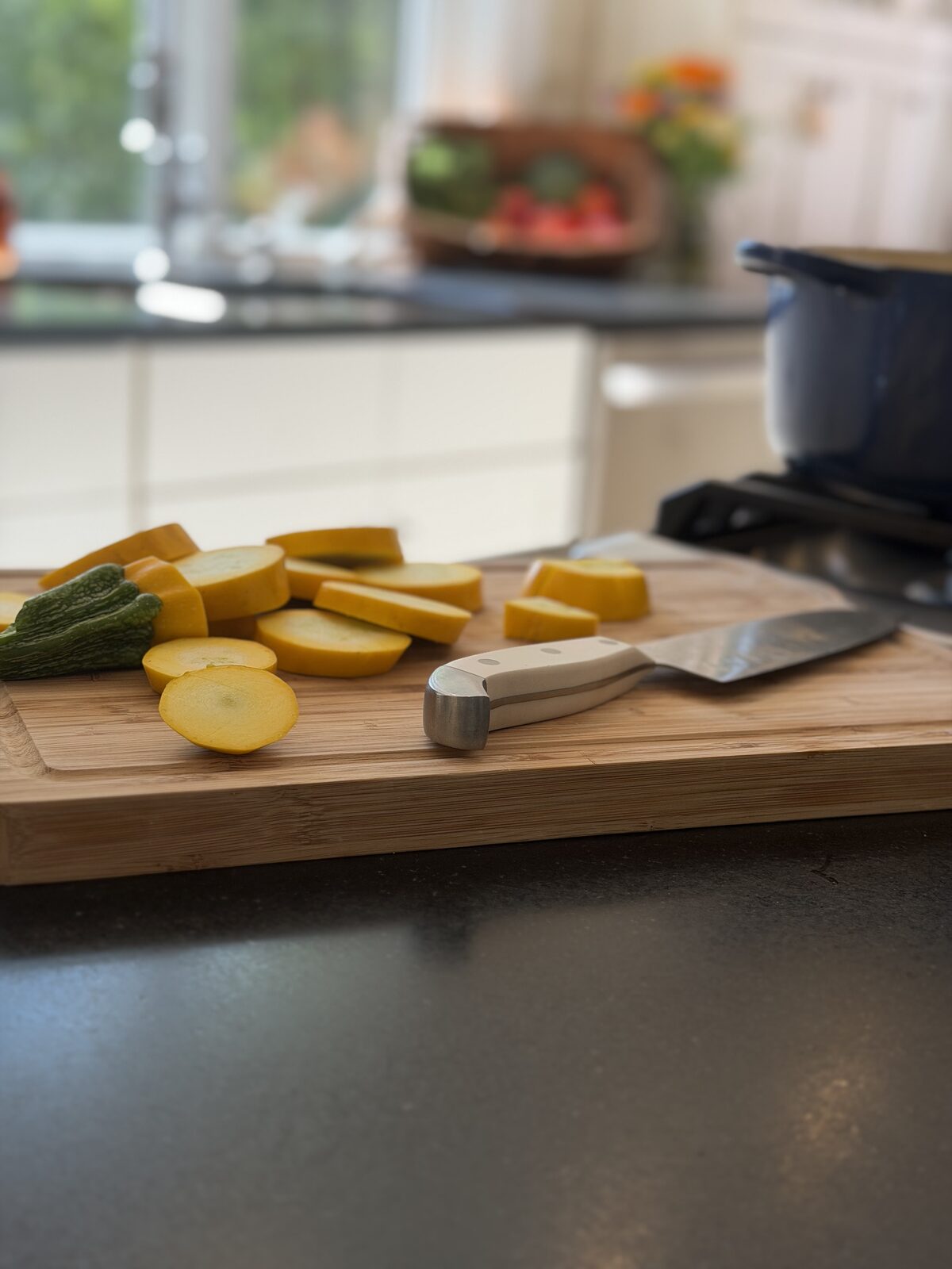 Sliced yellow squash on a bamboo board in a sunlit kitchen